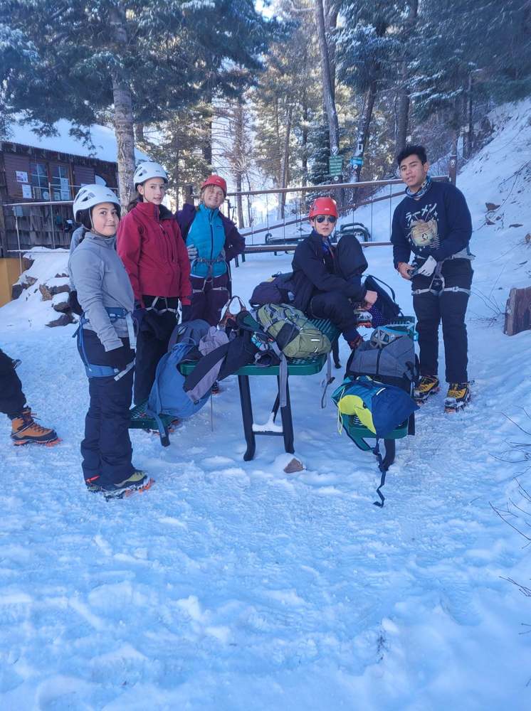 students in ice climbing gear gathered at table for picture