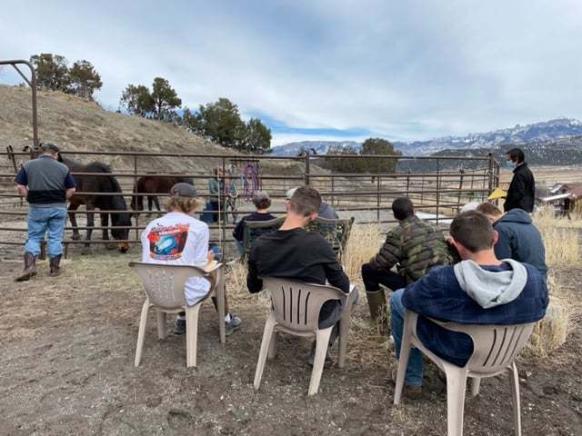 students outside horse stable in chairs taking notes