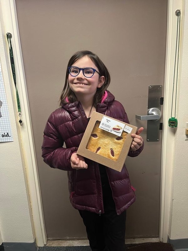 student smiling holding pie for pi day
