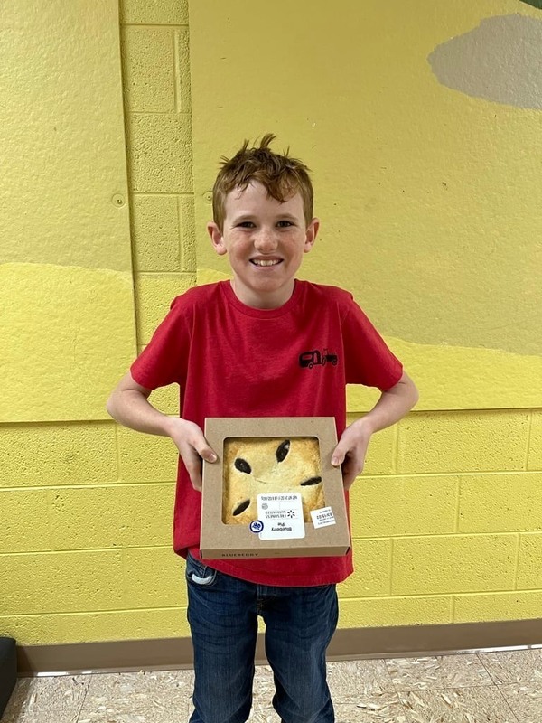 student smiling holding pie for pi day