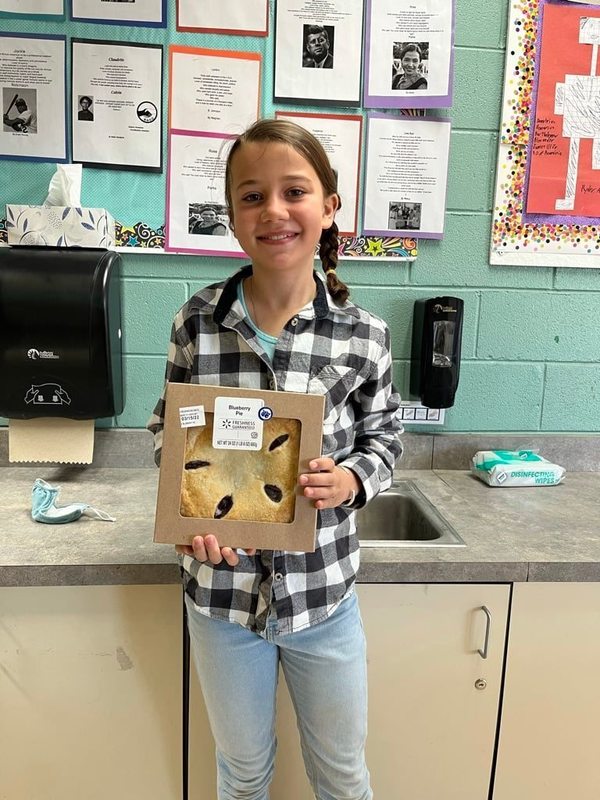 student smiling holding pie for pi day